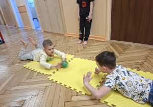 Na tym zdjęciu widać Marcela i Tymona z grupy III toczących piłeczkę nawzajem do siebie w leżeniu przodem.