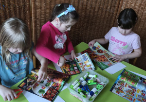 Zdjęcie przedstawia Wandę, Marcelinę Ł. i Kalinę wycinające obrazki do piramidy zdrowia.