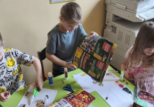 Zdjęcie przedstawia Stasia W., Klarę J. z koleżanką wycinających obrazki do piramidy zdrowia.