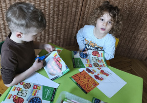 Zdjęcie przedstawia Adasia M. i Mikołaja z grupy III wycinających obrazki do piramidy zdrowia.