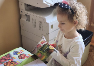 Zdjęcie przedstawia Oliwię z grupy III wycinającą obrazki do piramidy zdrowia.