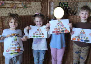 Zdjęcie przedstawia Mikołaja, Oliwię i Adasia M. z koleżanką z grupy III prezentujących wykonane przez siebie piramidy zdrowia.