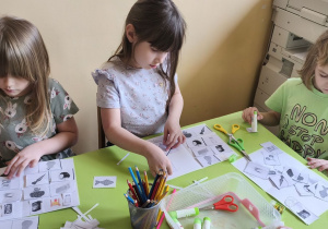 Zdjęcie przedstawia troje dzieci z grupy IV wykonujących pracę na temat "Produkty zdrowe i niezdrowe".