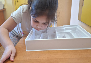 Zdjęcie przedstawia Olę z grupy IV wykonującą ćwiczenie oddechowe "Labirynt".