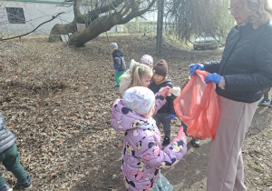 Zdjęcie przedstawia dzieci porządkujące teren w okolicy przedszkola.