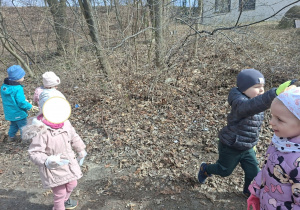 Zdjęcie przedstawia dzieci porządkujące teren w okolicy przedszkola.