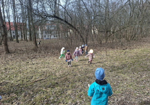 Zdjęcie przedstawia dzieci porządkujące teren w okolicy przedszkola.