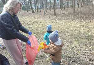 Zdjęcie przedstawia dzieci porządkujące teren w okolicy przedszkola.