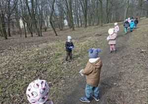 Zdjęcie przedstawia dzieci porządkujące teren w okolicy przedszkola.