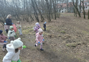 Zdjęcie przedstawia dzieci porządkujące teren w okolicy przedszkola.