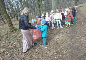 Zdjęcie przedstawia dzieci porządkujące teren w okolicy przedszkola.