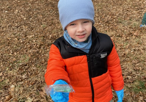 Zdjęcie przedstawia dzieci porządkujące teren parku w pobliżu przedszkola.