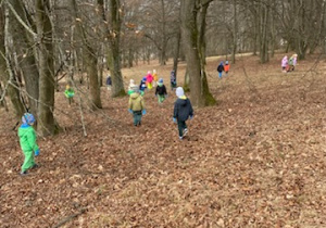 Zdjęcie przedstawia dzieci porządkujące teren parku w pobliżu przedszkola.