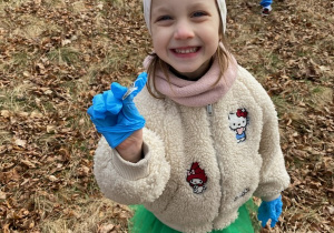 Zdjęcie przedstawia dzieci porządkujące teren parku w pobliżu przedszkola.