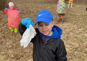Zdjęcie przedstawia dzieci porządkujące teren parku w pobliżu przedszkola.