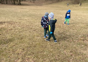 Zdjęcie przedstawia dzieci porządkujące teren parku w pobliżu przedszkola.