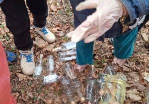 Zdjęcie przedstawia dzieci podczas porządkowania najbliższego terenu wokół przedszkola.