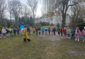 Na tym zdjęciu widać dzieci z grupy III i IV we wspólnym kole w ogrodzie przedszkolnym oraz nauczycielkę z Marzanną.
