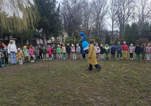Na tym zdjęciu widać dzieci z grupy II i III we wspólnym kole w ogrodzie przedszkolnym oraz nauczycielkę z Marzanną.
