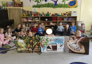 Na tym zdjęciu widać dzieci, które prezentują plansze, na podstawie których prowadzący opowiadał, jak powstaje czekolada.