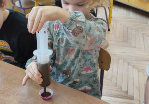 Na tym zdjęciu widać Oliwię, która napełnia foremkę płynną czekoladą.