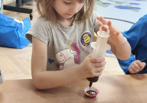 Na tym zdjęciu widać jedną z dziewczynek, która napełnia foremkę płynną czekoladą.