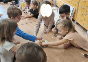 Zdjęcie przedstawia dzieci, które ozdabiają swoje pralinki.