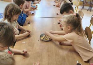 Zdjęcie przedstawia dzieci, które ozdabiają swoje pralinki.