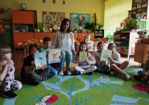 Zdjęcie przedstawia mamę Kuby oraz dzieci prezentujące książeczki przyniesione przez naszego gościa.