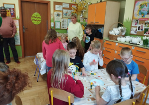 Na tym zdjęciu widać dzieci wykonujących pracę plastyczną oraz kilkoro rodziców.