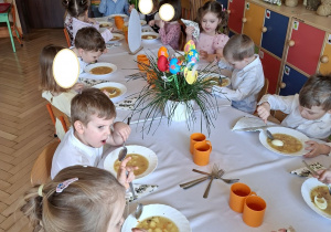 Na tym zdjęciu widać dzieci spożywające świąteczny żurek z jajkiem.