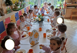 Zdjęcie przedstawia dzieci przy świątecznym stole, spożywające drugie danie.