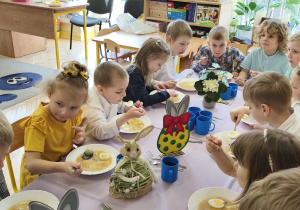 Zdjęcie przedstawia dzieci przy świątecznym stole, spożywające żurek z jajkiem.