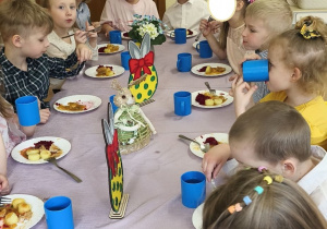 Na tym zdjęciu widać dzieci siedzące przy świątecznym stole, spożywajace drugie danie.