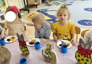 Na tym zdjęciu widać dzieci siedzące przy świątecznym stole, spożywajace drugie danie.