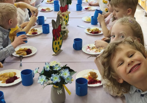 Na tym zdjęciu widać dzieci siedzące przy świątecznym stole, spożywajace drugie danie.