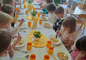 Zdjęcie przedstawia dzieci siedzące przy świątecznym stole, spożywające żurek z jajkiem.