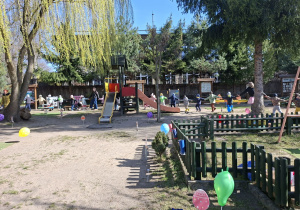 W tle zdjęcia widać korowód dzieci podążający za zajączkiem wielkanocnym.