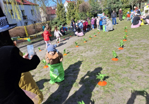 Zdjęcie przedstawia dzieci skaczące w workach między marchewkami.