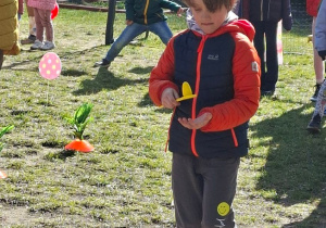 Zdjęcie przedstawia Tymka przenoszącego jajko na łyżce oraz pozostałe dzieci stojące z tyłu.