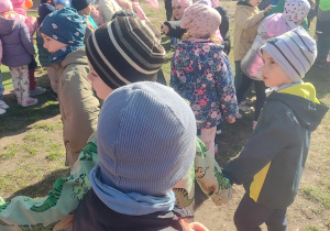 Na tym zdjęciu widać dzieci stojące w ogrodzie przedszkolnym oczekujące na zabawy.