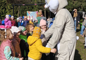 Zdjęcie przedstawia dzieci witające się z wielkanocnym zajączkiem.
