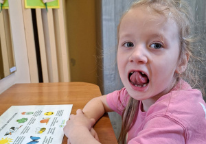 Zdjęcie przedstawia Julę P. z grupy III wykonującą ćwiczenia narządów mowy.