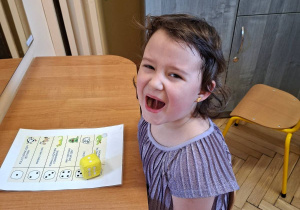 Na tym zdjęciu widać Lilę z grupy III podczas wykonywania ćwiczeń narządów mowy z przyborem.