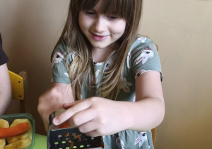 Zdjęcie przedstawia Alę W. z grupy IV ścierającą na tarce marchewkę.