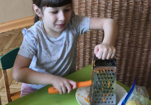 Zdjęcie przedstawia Kalinę z grupy IV ścierającą na tarce marchewkę.