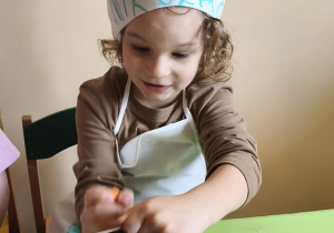 Zdjęcie przedstawia Mikołaja z grupy III ścierającego na tarce marchewkę.