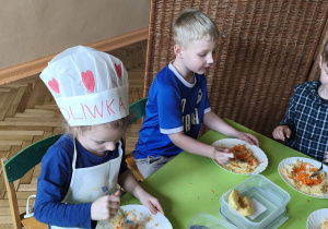 Zdjęcie przedstawia Oliwię, Adama W. i Adama M. z grupy III mieszających starte na tarce składniki surówki.