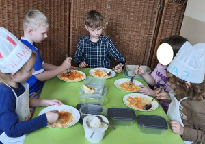 Zdjęcie przedstawia pięcioro dzieci z grupy III mieszających składniki surówki.