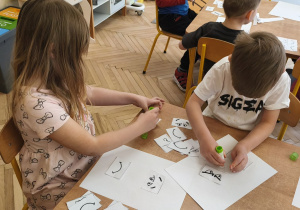 Zdjęcie przedstawia dwoje dzieci wykonujących kartę pracy.